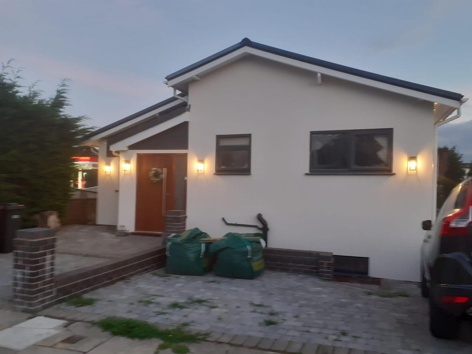 Same bungalow after renovation, white render finish, dusk