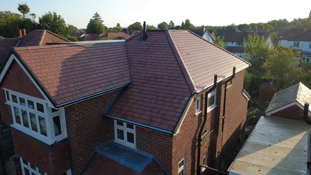 Aerial drone photograph of a large red-brick house with a freshly tiled roof, captured by JPN Building Contractors in Bolton