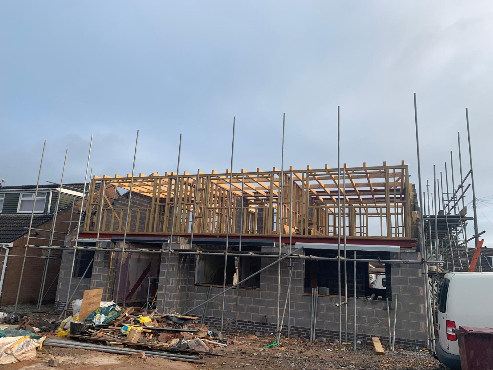 Timber roof trusses being installed on a rear extension, blockwork walls visible