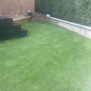 New artificial lawn with raised timber steps and brick retaining wall