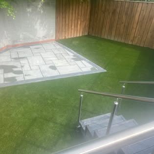 Grey porcelain paving inset into a new artificial lawn with timber fencing